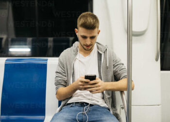 Young man using smartphone | FintechZoom