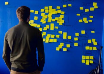 man in grey standing in front of a blue board with results of brainstorming session