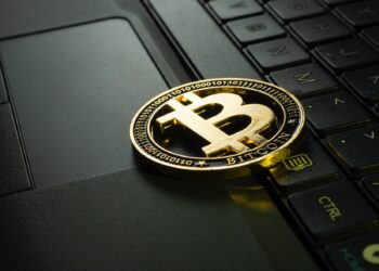 Golden bitcoin over a black laptop