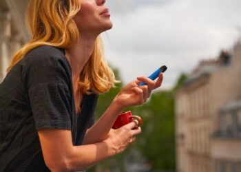 woman with a cup in the hand and a vape on the other hand