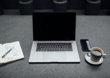 Laptop between cup of coffee and book