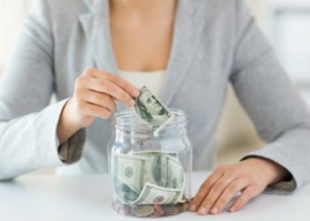 Woman inserting banknotes into a glass cup