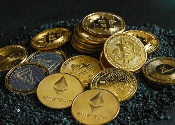 A group of gold cryptocurrency coins on top of black stones