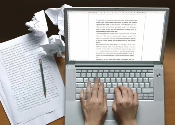 Person using laptop to write a book | FintechZoom