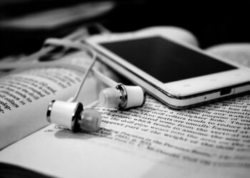 Mobile and headphones over book | FintechZoom