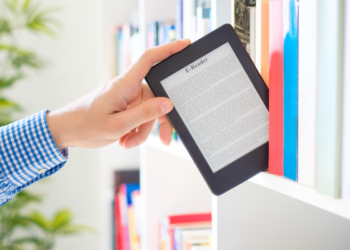 Person removing ebooks tablet from a library shelf | FintechZoom