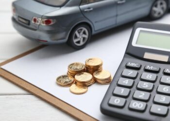Desk with Paper, calculator, coins and a Toy Car | FintechZoom
