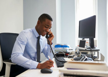 Business Men on desk using phone | FintechZoom