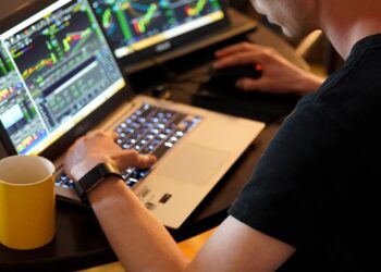 Man using laptop to trading in stock market - FintechZoom