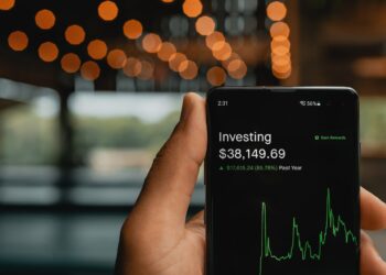 Person holding phone with stock chart - FintechZoom