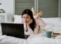 Indian Women watch Movies on her laptop in her bed - FintechZoom
