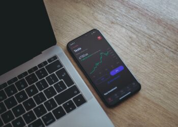 Mobile with Tesla Stock Chart near Laptop | FintechZoom