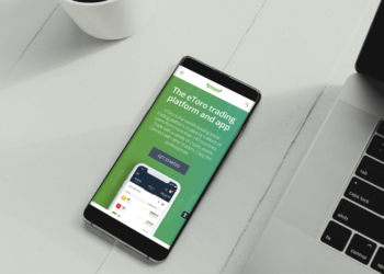 Mobile on white table with eToro app open | FintechZoom