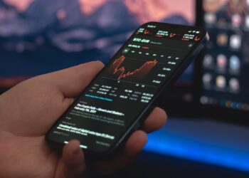 Person holding mobile phone with a Stocks App opened | FintechZoom