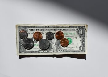 One dollar and coin over white table | FintechZoom