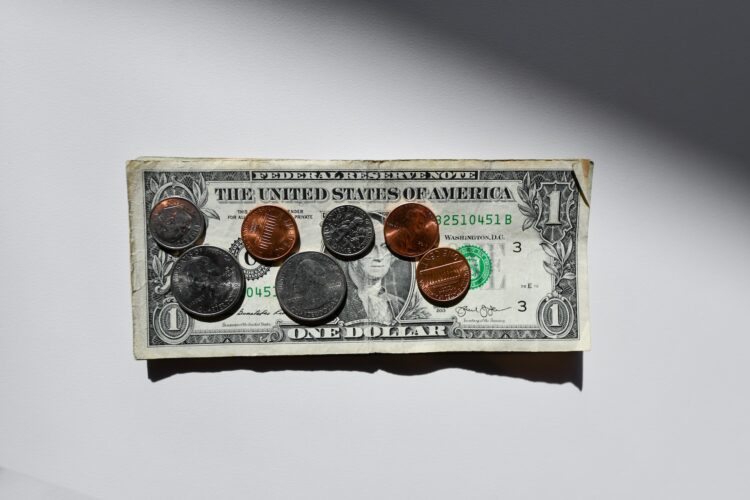 One dollar and coin over white table | FintechZoom