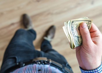 Man with Dollar in Hand | FintechZoom