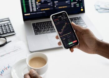 Person holding a Smartphone with Stock Trading app | FintechZoom
