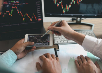 Two investors are working together to analyze Stock Charts | FintechZoom