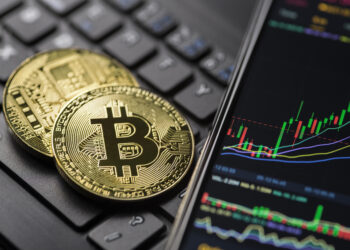 Bitcoin gold cryptocurrency trading chart on smartphone close up | FintechZoom