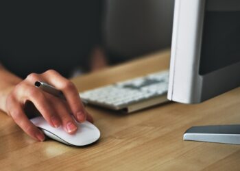 Person working on computer wit hand on mouse | FintechZoom