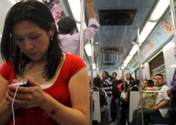 Woman using mobile phone in Metro subway, Balderas Station Mexico | FintechZoom