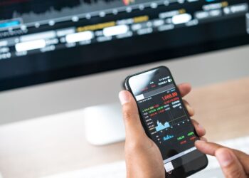 Businessman using a mobile phone to check stock market data | FintechZoom