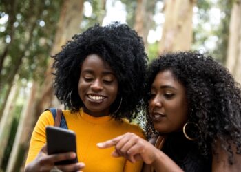 African women looking to her mobile phone | FintechZoom