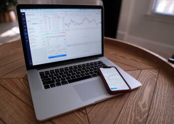 Laptop and mobile with stock market charts | FintechZoom