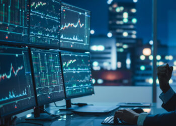 Man smiling for 6 monitors with trading charts | FintechZoom