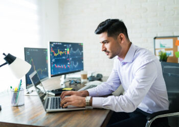 Broker trading through laptop at desk while working from home | FintechZoom