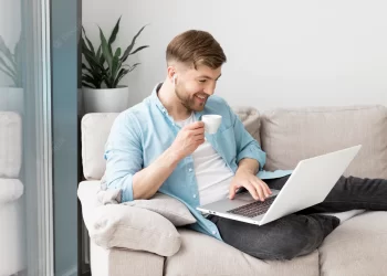Man drinking coffee using laptop | FintechZoom