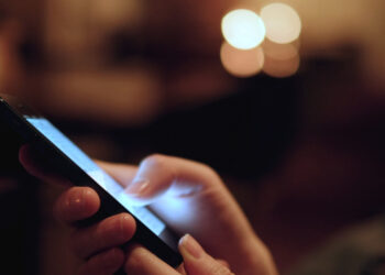 Person using a Phone in the dark | FintechZoom
