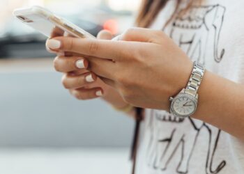 Woman holding iPhone | FintechZoom