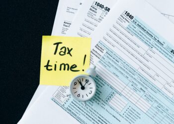 Tax Forms with post it to remember tax time | FintechZoom