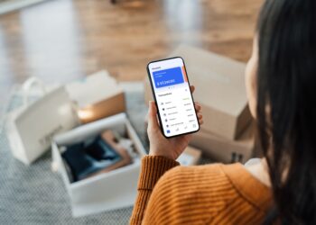 A woman holding phone banking app | FintechZoom