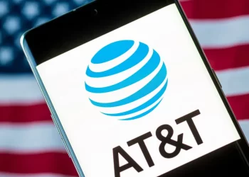 ATT logo on smartphone phone over american flag | FintechZoom