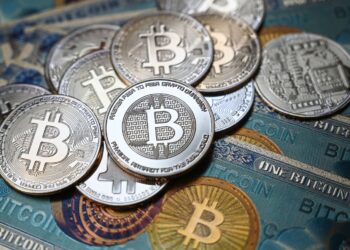 Bitcoins over blue table | FintechZoom