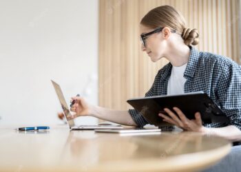 Young woman using laptop for her bills | FintechZoom