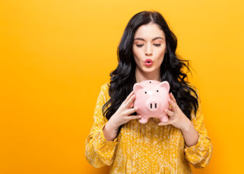 Young girl holding a money pig | FintechZoom