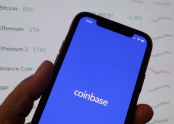Person holding a smartphone with Coinbase App | FintechZoom