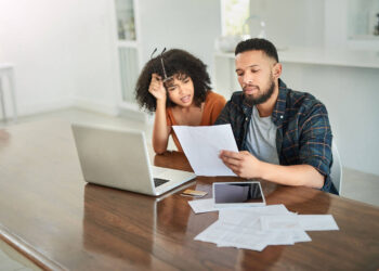 Couple looking to their bills | FintechZoom