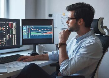 Trading Man working with charts and market reports on computer screens | Top Penny Stocks | FintechZoom
