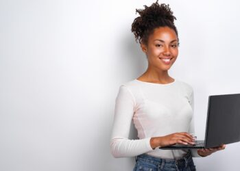 Happy young woman holding laptop computer | FintechZoom