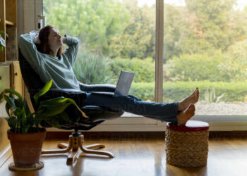 Young woman at home on Laptop | FintechZoom