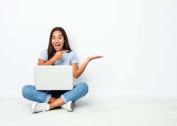Young mixed race indian woman sitting on laptop | FintechZoom