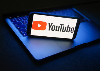 Smartphone with youtube app over laptop | FintechZoom