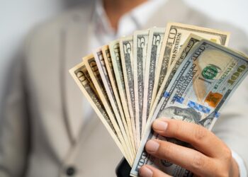 Business man with dollars in hand | FintechZoom