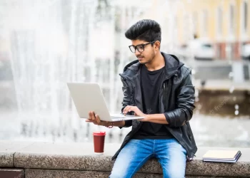 Indian man with laptop | FintechZoom