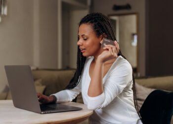 Happy Woman holding a credit card | FintechZoom